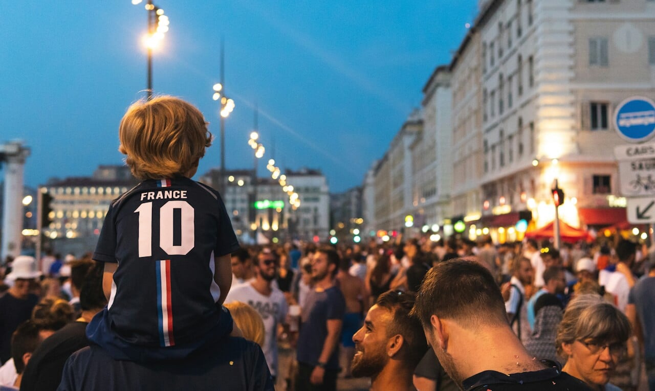 Kind mit Frankreich-Trikot sitzt auf Papas Schultern beim Feiern auf der Fanmeile