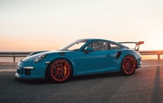 Blauer Porsche mit roten Felgen im Sonnenuntergang